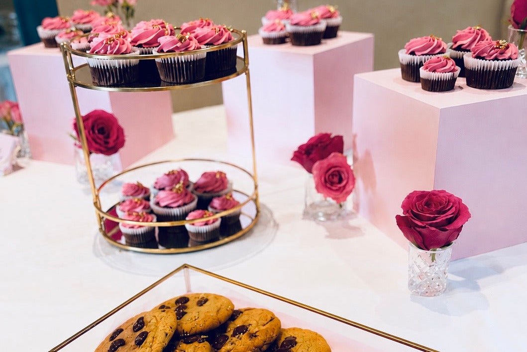 Ein Sweet Table Setup mit rosa Cupcakes auf einer goldenen Etagere angerichtet und mit Rosen dekoriert von Goldzucker in Ostfildern bei Stuttgart